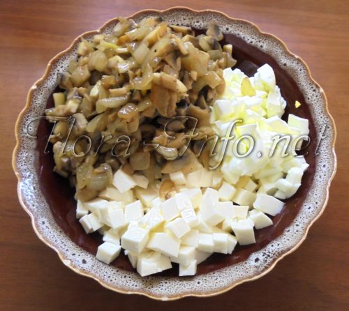 Порезанный сыр, обжаренные с луком грибы и яичные белки на салат с грибами